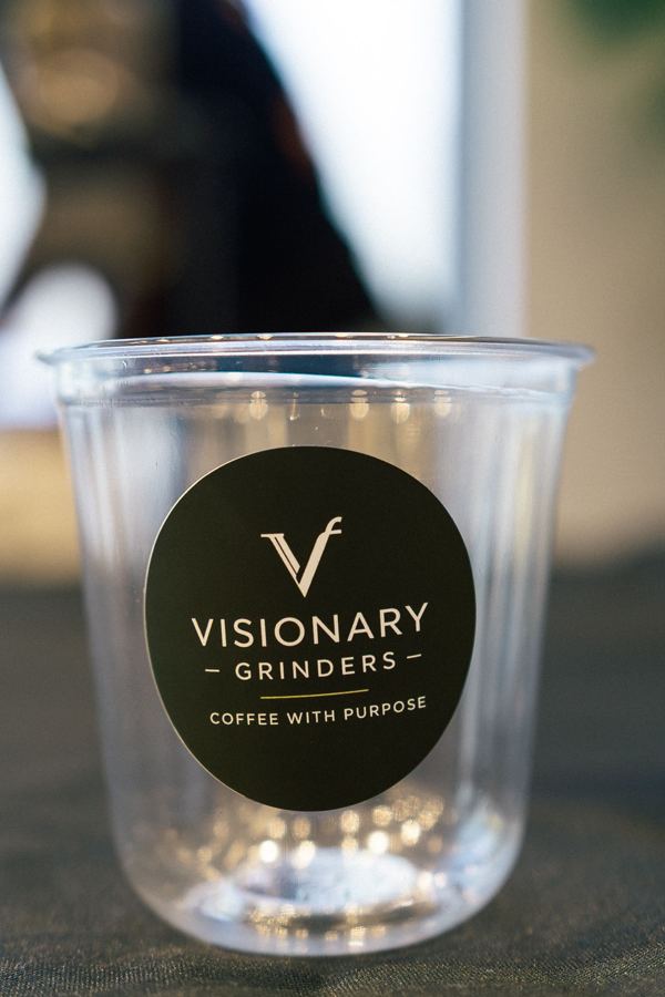 Clear Visionary Grinders cup with the Coffee with Purpose label